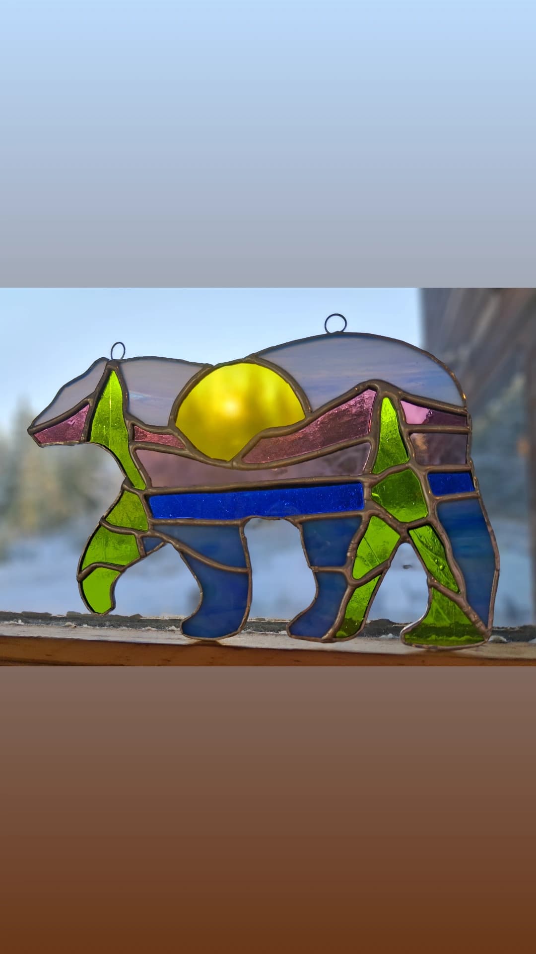 Bear silhouette stained glass with mountain sunset landscape inside