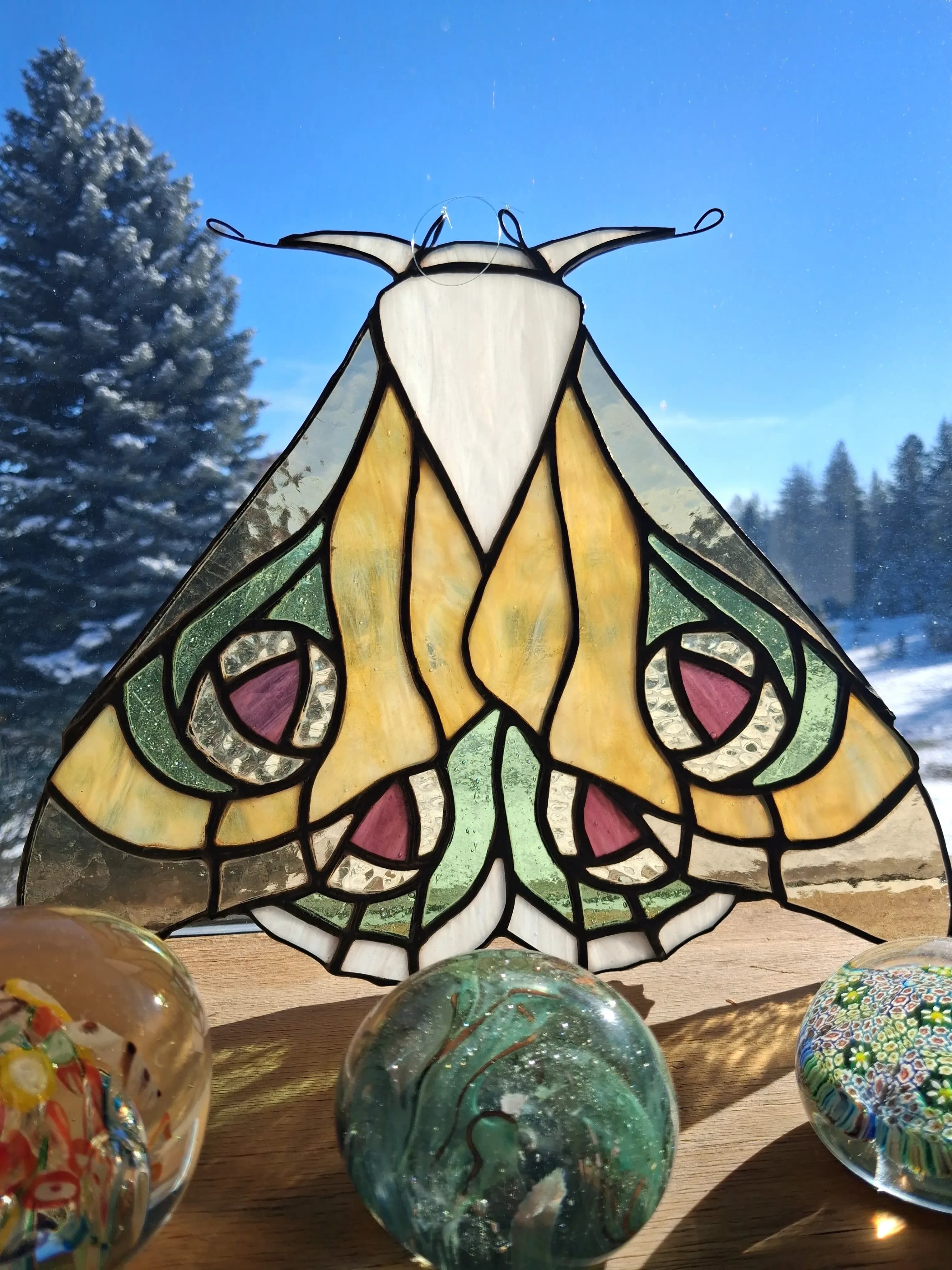 Golden and green stained glass moth suncatcher with pink eyespots and glass paperweights