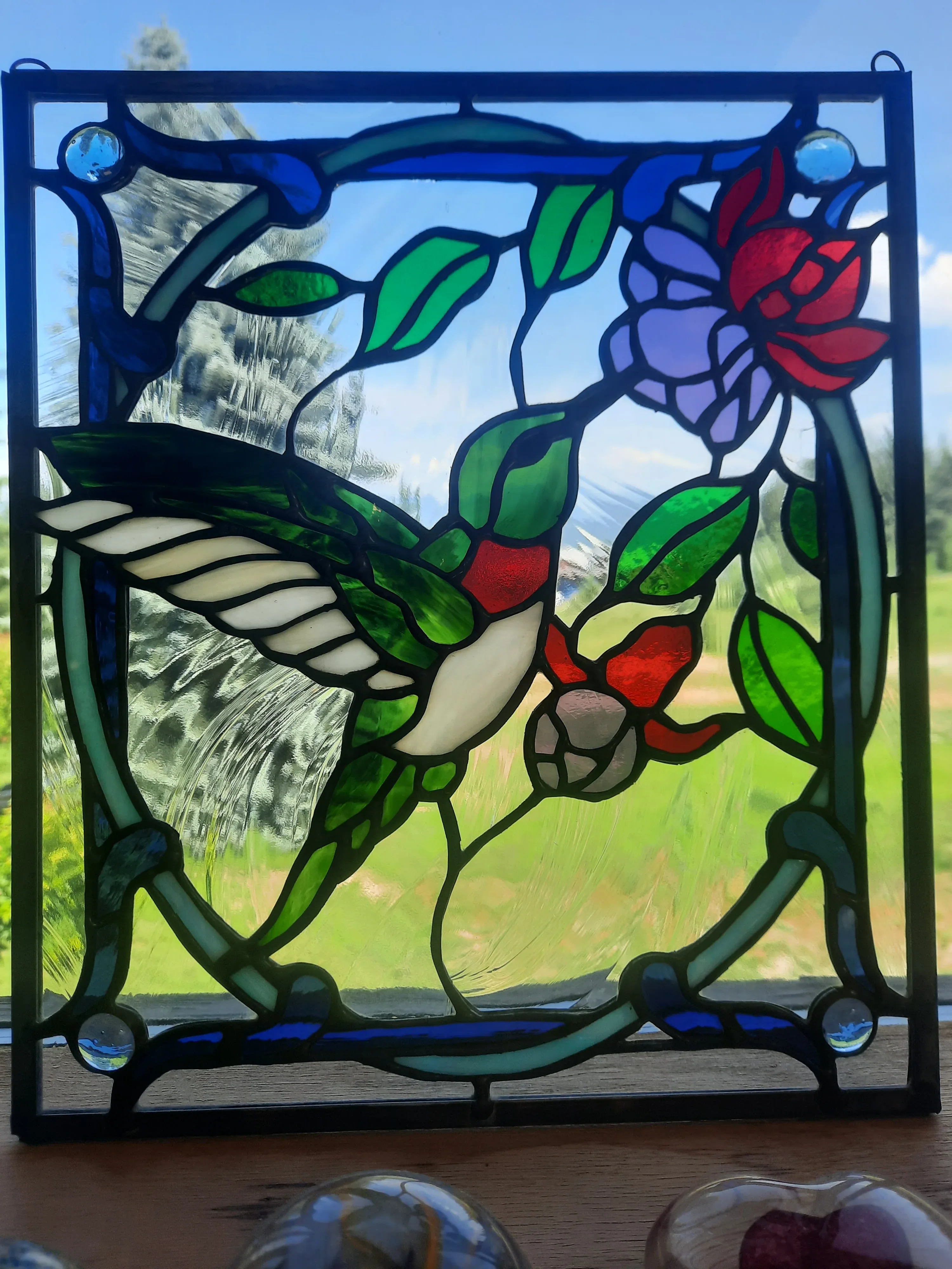 Stained glass hummingbird with red and purple flowers - square window panel